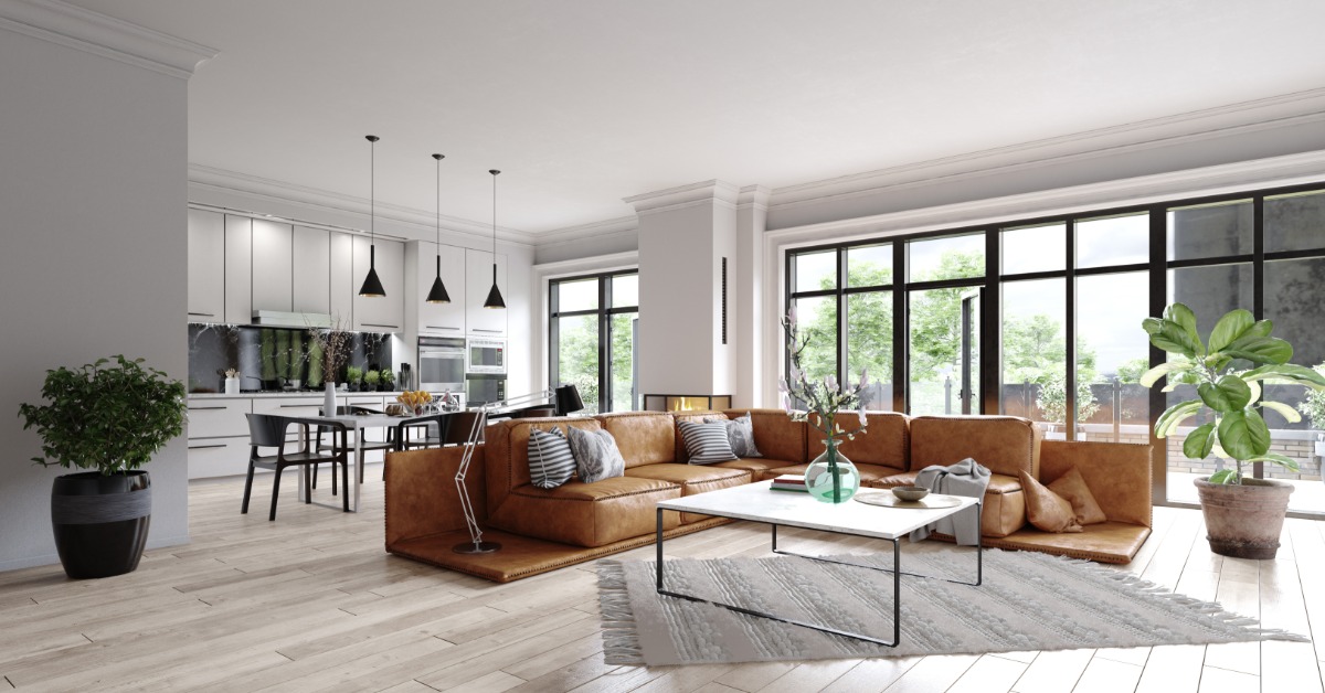 A large modern living room with a leather L-shaped sectional couch, with floor-to-ceiling windows next to the kitchen.