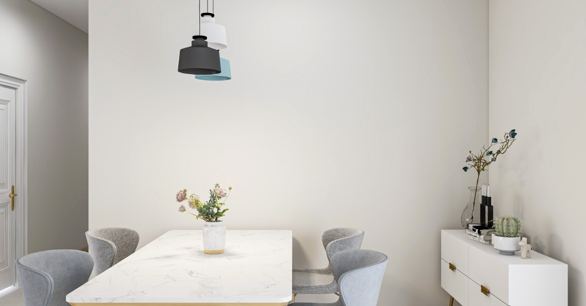 A marble dining table with four grey velvet chairs, next to a white credenza, and under a chandelier with three lights.
